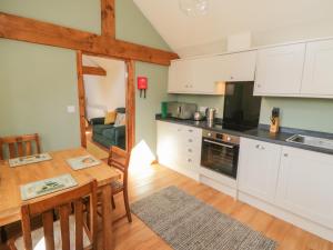 a kitchen with white cabinets and a wooden table at Yeoman's Cottage in Pickering