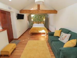 a living room with a green couch and a bed at Yeoman's Cottage in Pickering