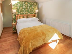 Un dormitorio con una cama con una manta amarilla. en Yeoman's Cottage, en Pickering