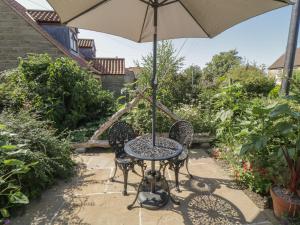 a table and chairs with an umbrella on a patio at Yeoman's Cottage in Pickering