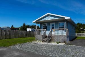 a small blue house with a wooden fence at Peck's Housekeeping Cottages in Louisbourg