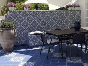 eine Terrasse mit einem Tisch und Stühlen auf einem blauen Fliesenboden in der Unterkunft Casa Vacanze Ibiscus in Alcamo Marina