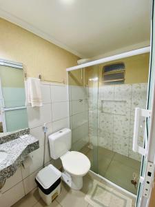 a bathroom with a toilet and a glass shower at Hotel Pousada Marra in Catalão