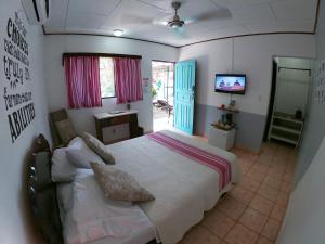 a bedroom with a bed and a television in it at Hotel Perico Azul & Surf Camp in Jacó