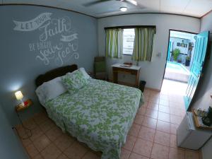 a bedroom with a bed and a desk and a window at Hotel Perico Azul & Surf Camp in Jacó