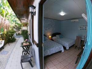a small room with two beds and a balcony at Hotel Perico Azul & Surf Camp in Jacó