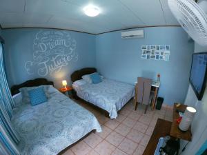 a bedroom with two beds and a sign on the wall at Hotel Perico Azul & Surf Camp in Jacó