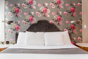 ein Schlafzimmer mit einem Bett mit rosa Blumen an der Wand in der Unterkunft Wicker Park Inn in Chicago