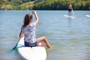 a woman sitting on a surfboard in the water at Glamping Lac du Causse in Lissac-sur-Couze