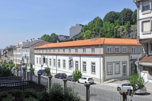 een wit gebouw met een oranje dak op een straat bij HI Braga - Pousada de Juventude in Braga