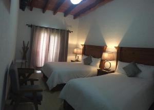 a hotel room with two beds and two lamps at Hotel Concierge Flor y Canto in Tepoztlán