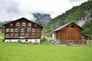 ein großes Gebäude auf einem Feld vor einem Berg in der Unterkunft Hof Erath in Au im Bregenzerwald