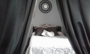 Chambre d'Hôtes La Marlotte في Castello-di-Rostino: غرفة نوم بسرير مع ستائر ومرآة
