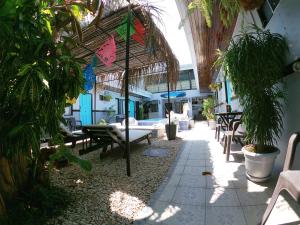 a patio with chairs and tables and an umbrella at Hotel Perico Azul & Surf Camp in Jacó