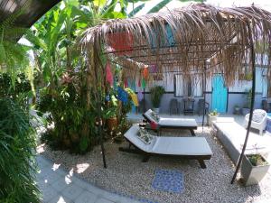 um jardim com um pavilhão com um sofá e mesas em Hotel Perico Azul & Surf Camp em Jacó
