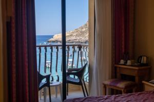 a bedroom with a view of the ocean from a balcony at Hotel San Andrea in Xlendi
