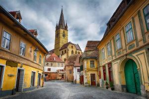 a city street with a clock tower in the distance at Apartament Mario in Sibiu