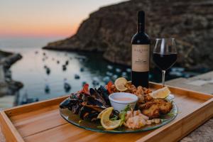 a plate of food with a bottle of wine and a glass at Hotel San Andrea in Xlendi