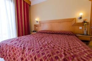 a bedroom with a large bed with a red comforter at Hotel San Andrea in Xlendi