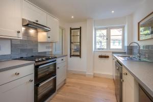 a kitchen with white cabinets and a stove top oven at Owl Cottage in Wighton +8 photos