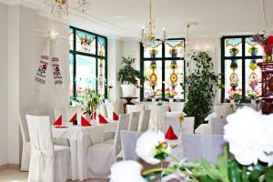 Ratskeller Hotel & Restaurant Lindow في ليندو: غرفة بها طاولات وكراسي بيضاء ونوافذ زجاجية ملطخة