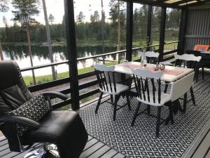 a porch with a table and chairs and a view of a lake at Tallbacken Fritidsby in Brännan
