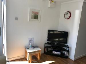 a living room with a tv and a table and a clock at Kiki’s Corner in Newquay