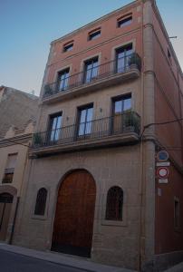 a tall brick building with a door and a balcony at La Casa Del Miracle in Balaguer
