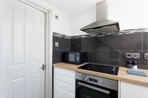 uma cozinha com um lavatório e um fogão forno superior em Stopover at ORCHARD LOFT, cosy and convenient em Portsmouth