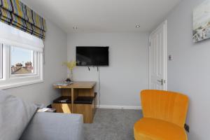 a living room with a couch and a tv and a chair at Stopover at ORCHARD LOFT, cosy and convenient in Portsmouth