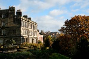 an old stone building with trees in front of it at Teesdale Rooms in Whitby