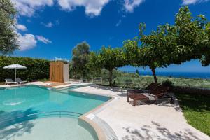 a swimming pool with two chairs and the ocean at TheTree Villa, Magical Scenery Experience, By ThinkVilla in Gállos