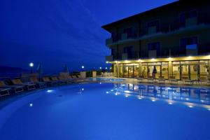 a large swimming pool in front of a building at night at All Inclusive Hotel Piccolo Paradiso in Toscolano Maderno