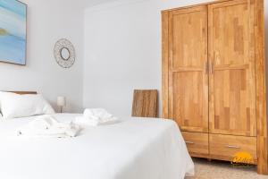 een slaapkamer met een wit bed en een houten kast bij Casa Genoves by Cadiz Time in Cádiz
