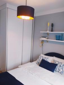 - une chambre avec un lit blanc et une lumière au-dessus dans l'établissement Apartament Niebieski, à Świnoujście