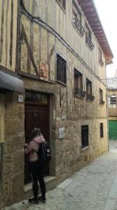 a woman with a backpack standing outside of a building at CASONA de los Peregrinos I in Cepeda