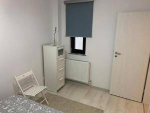 um quarto com uma cama, uma cadeira e uma janela em Apartment Pitesti em Piteşti