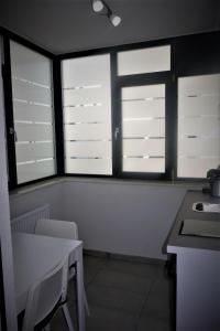 ピテシュティにあるApartment Pitestiの窓3つ、テーブルと椅子付きのキッチン