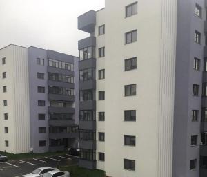 a white apartment building with cars parked in a parking lot at Apartment Pitesti in Piteşti