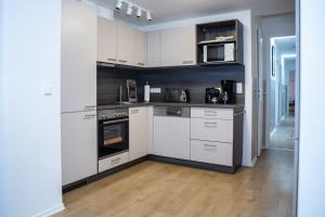 a small kitchen with white cabinets and appliances at H&H Apartments im Herzen der Stadt geräumig ruhig zentral mit Küche und Esstisch in Greifswald +40 photos