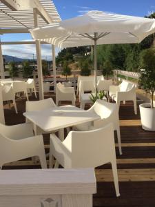 a patio with white tables and chairs and an umbrella at Hotel Rosalía in Padrón