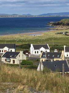 eine Gruppe von Häusern auf einem Hügel neben dem Meer in der Unterkunft Beach View Heights Dugort Achill Eircode F28E8D9 in Doogort