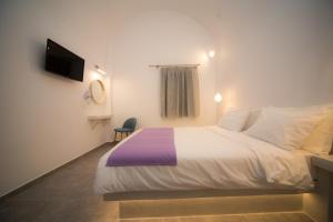 a bedroom with a white bed and a tv at Markakis Studios Fira Town in Fira