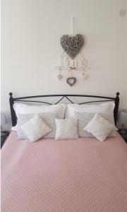 łóżko z białymi poduszkami i sercem na ścianie w obiekcie Studio Al Ponto w Rovinj