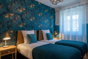 two beds in a bedroom with a blue wall at Le Leon Bourgeois 6 pers Hypercentre Epernay in Épernay
