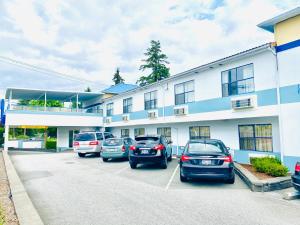 un gruppo di auto parcheggiate in un parcheggio di fronte a un edificio di Happy Day Inn a Burnaby