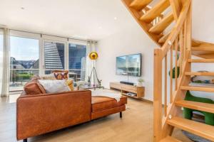 Una sala de estar con un sofá y una escalera. en Suite Windrose, en Zingst