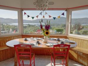 ein Esszimmer mit Tisch, Stühlen und Fenstern in der Unterkunft Grenane Heights in Kenmare