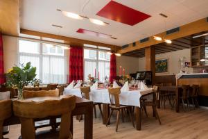 a dining room with tables and chairs and windows at Hotel du Pont in Gampel