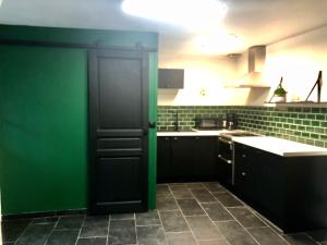 eine Küche mit grünen Wänden und einer schwarzen Tür in der Unterkunft Le charme et l’original in Ailly-le-Haut-Clocher